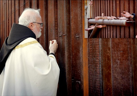 L’arcivescovo di Boston O’Malley dà la comunione a migranti dall’altra parte del muro di frontiera