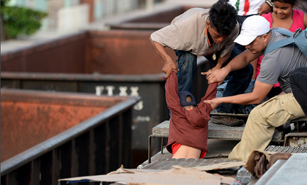 Un bambino dell’America Centrale è aiutato a salire sul tetto del treno per iniziare il viaggio verso gli Stati Uniti. Foto Esteban Biba/Soy502