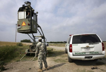 Un membro della Guardia Nazionale osserva un suo collega della Pattuglia di Frontiera in un Skybox (Foto AP)